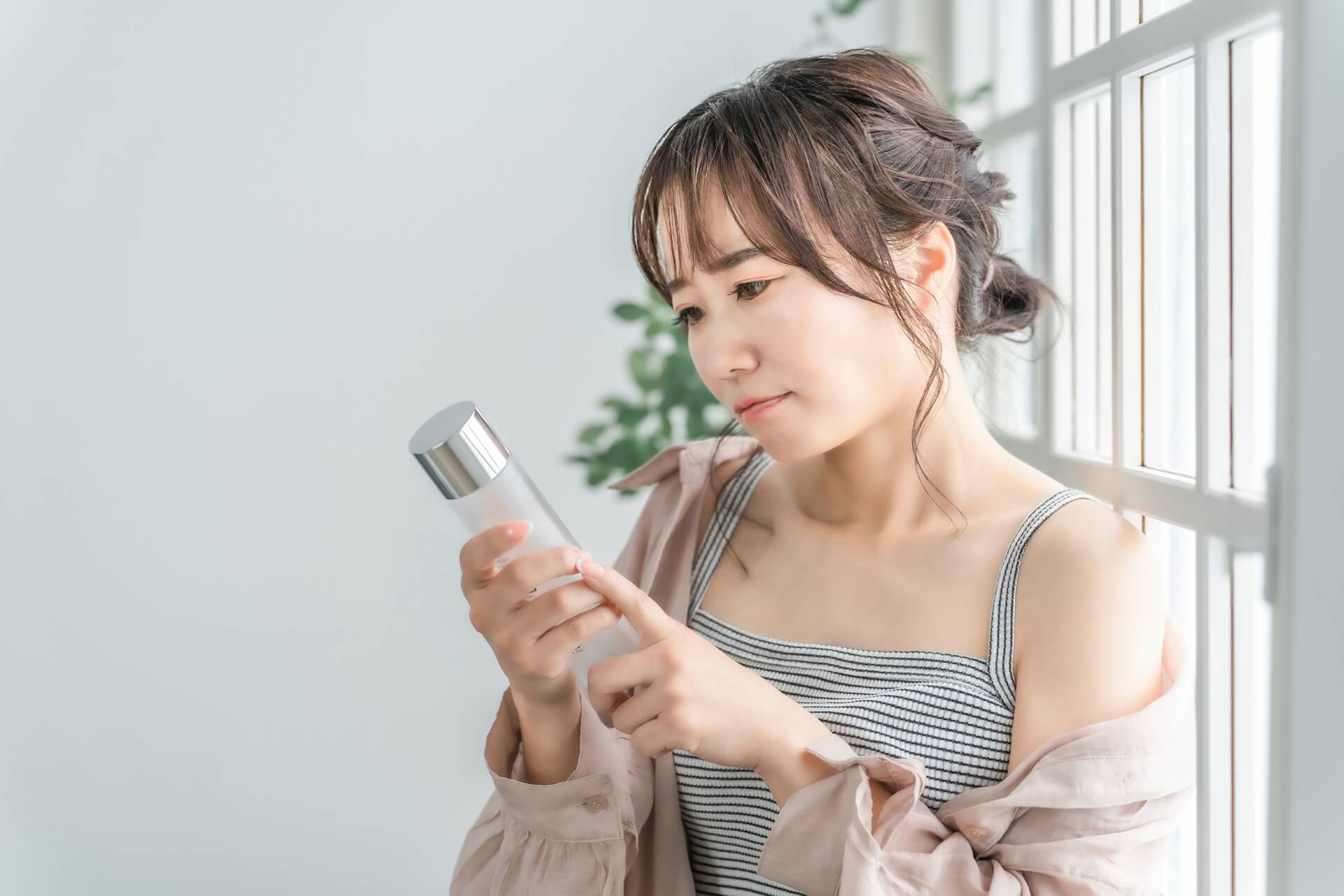 日差しを浴びながら化粧品を確認する女性