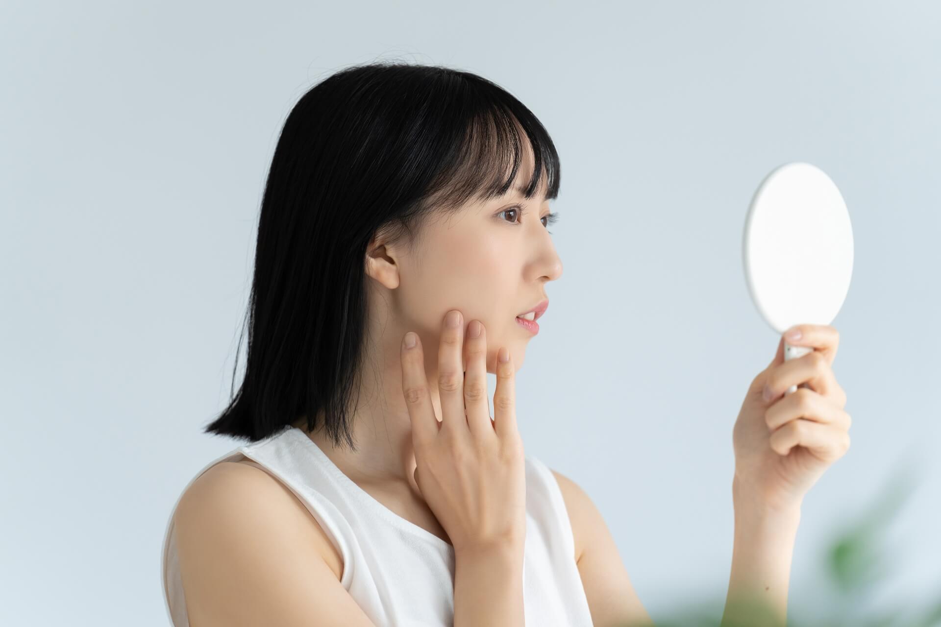 鏡を見て肌を確認する女性